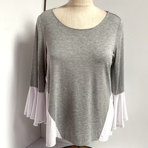 Two-tone pullover top in lightweight gray knit with white bell sleeves.